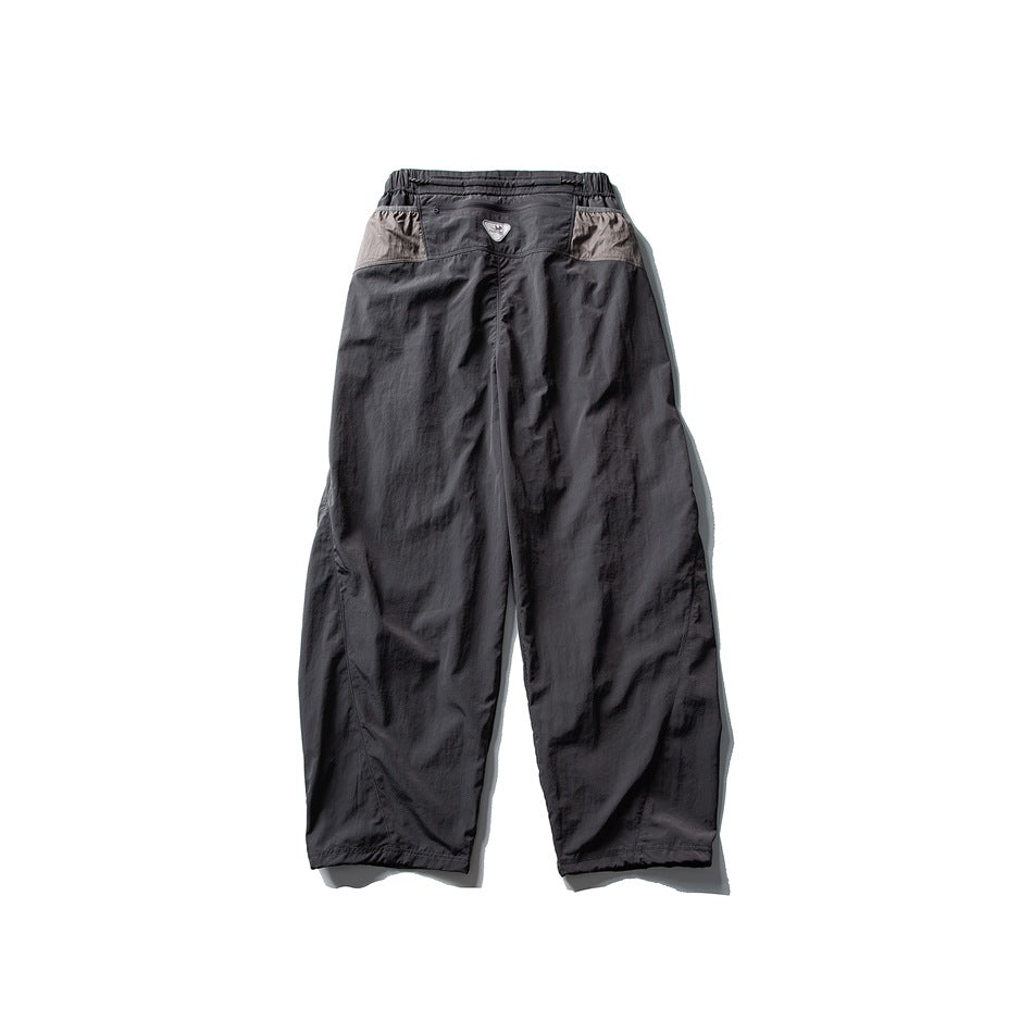 Back view of charcoal-gray wide-leg pants with a gathered elastic waist and light contrasting panels at the hips.