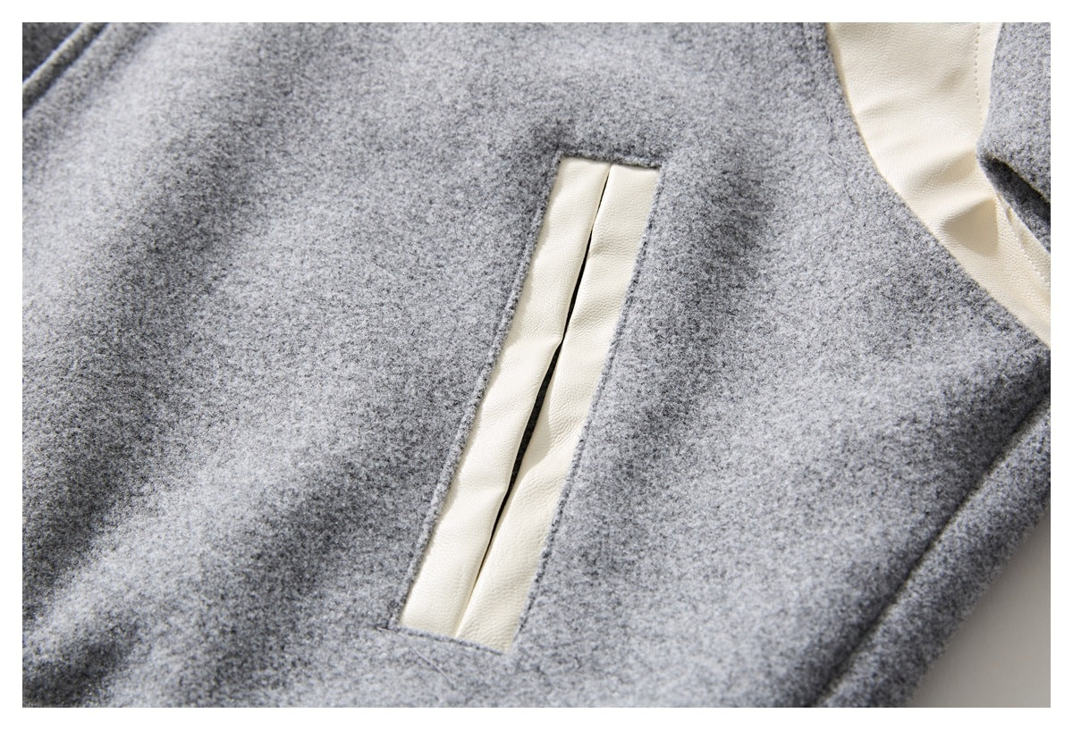 Close-up of a narrow vertical pocket opening edged with cream trim on gray fabric.
