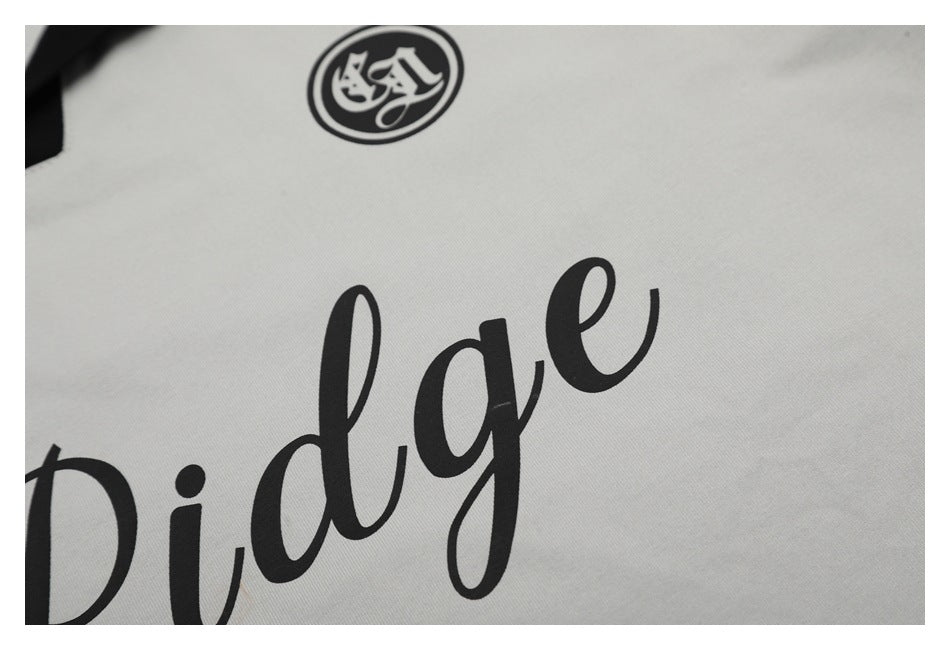 Close-up of black cursive lettering and a circular emblem printed on light-colored fabric.