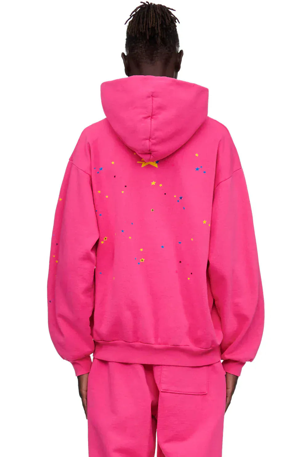 Person wearing a Sp5der “Nevermind the Punk” Hoodie – Hot Pink 440GSM Heavyweight Streetwear Pullover and matching pants, shown from the back. The hoodie has small multicolored stars and dots for a playful Y2K punk look.
