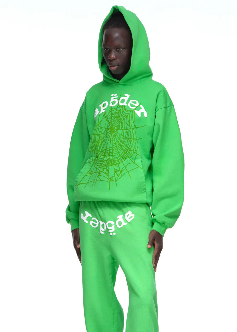 Someone in a Sp5der “Web Core” Hoodie – Neon Green 440GSM Heavyweight Oversized Streetwear Pullover and matching sweatpants, featuring “spider” text and a spiderweb graphic on the hoodie’s front.