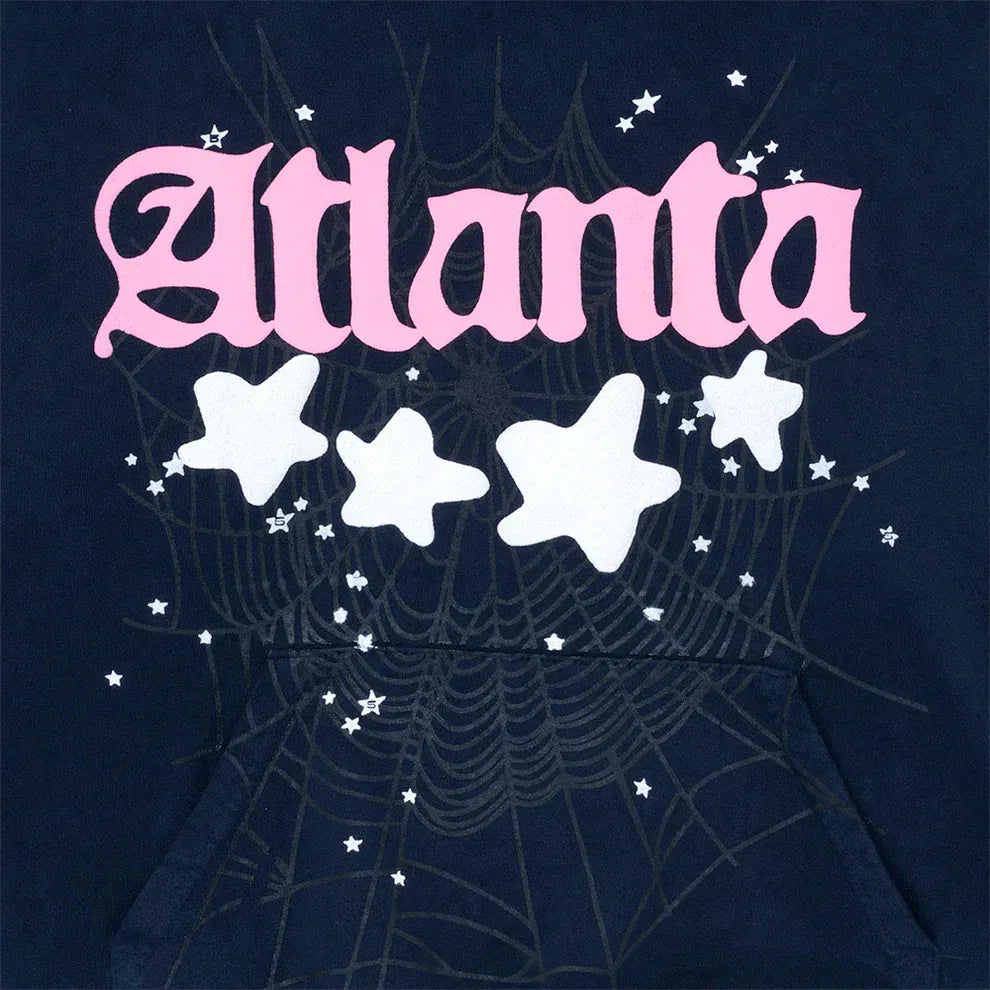 The Sp5der “Atlanta Nights” Web Hoodie in navy blue features large pink ‘Atlanta’ lettering, white stars, a subtle spiderweb print, and is made from 440GSM heavyweight cotton fleece for an oversized streetwear look.