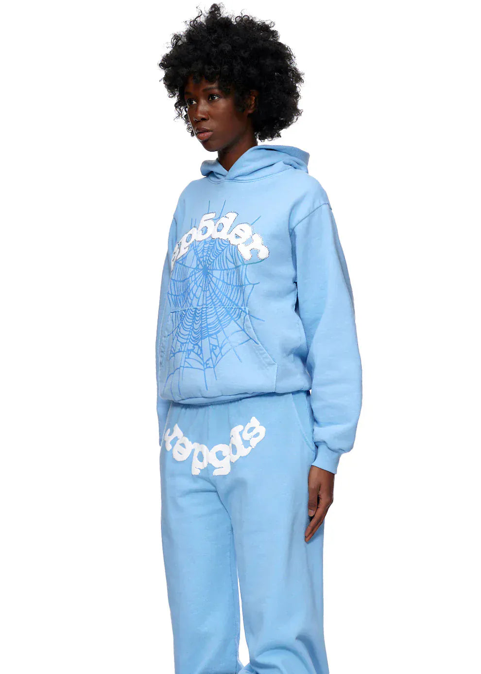 A person wears the Sp5der Hoodie – Sky Blue 440GSM Heavyweight Chenille Logo Spider-Web Streetwear Pullover and matching sweatpants, with white graphic text and a spiderweb front design for a bold streetwear look.