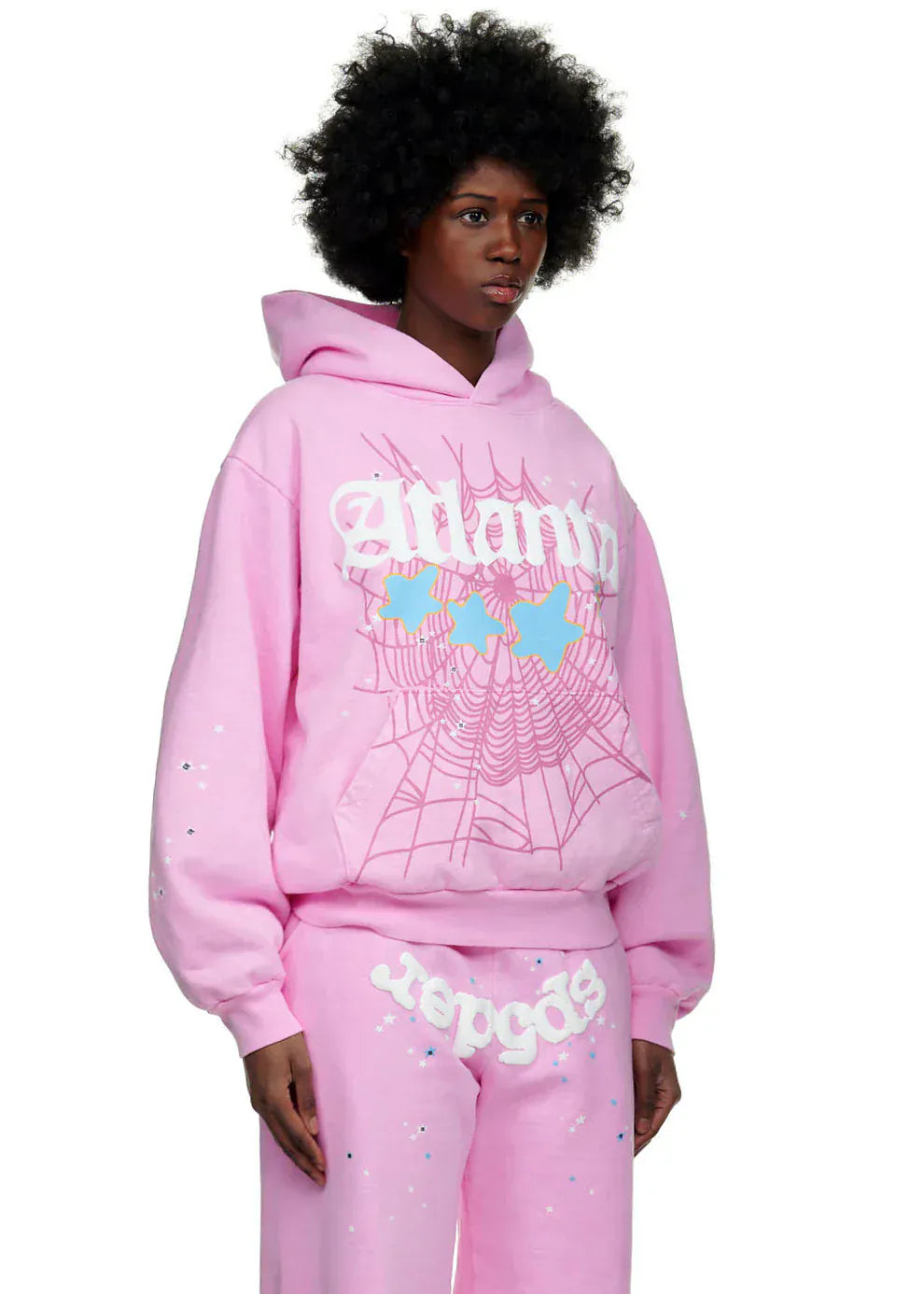 Wearing the Sp5der Atlanta Hoodie – Pink 440GSM Heavyweight Y2K Streetwear Pullover and matching pants with white and blue web graphic prints, a person channels bold Y2K streetwear vibes against a plain background.