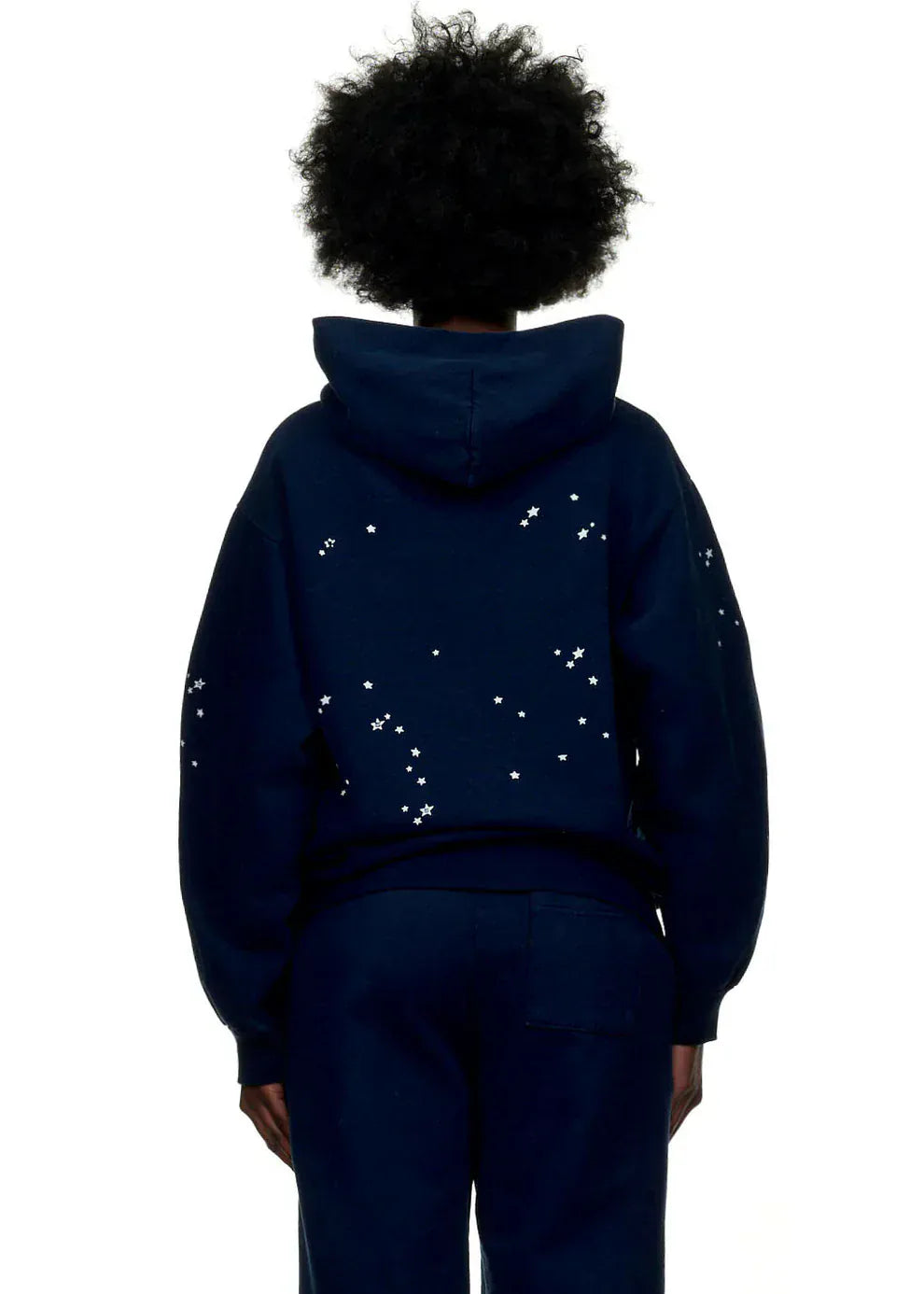 A person is seen from behind in a Sp5der “Atlanta Nights” Web Hoodie – Navy Blue 440GSM heavyweight oversized streetwear pullover, featuring scattered white stars on the back and sleeves for a stylish, comfortable look.