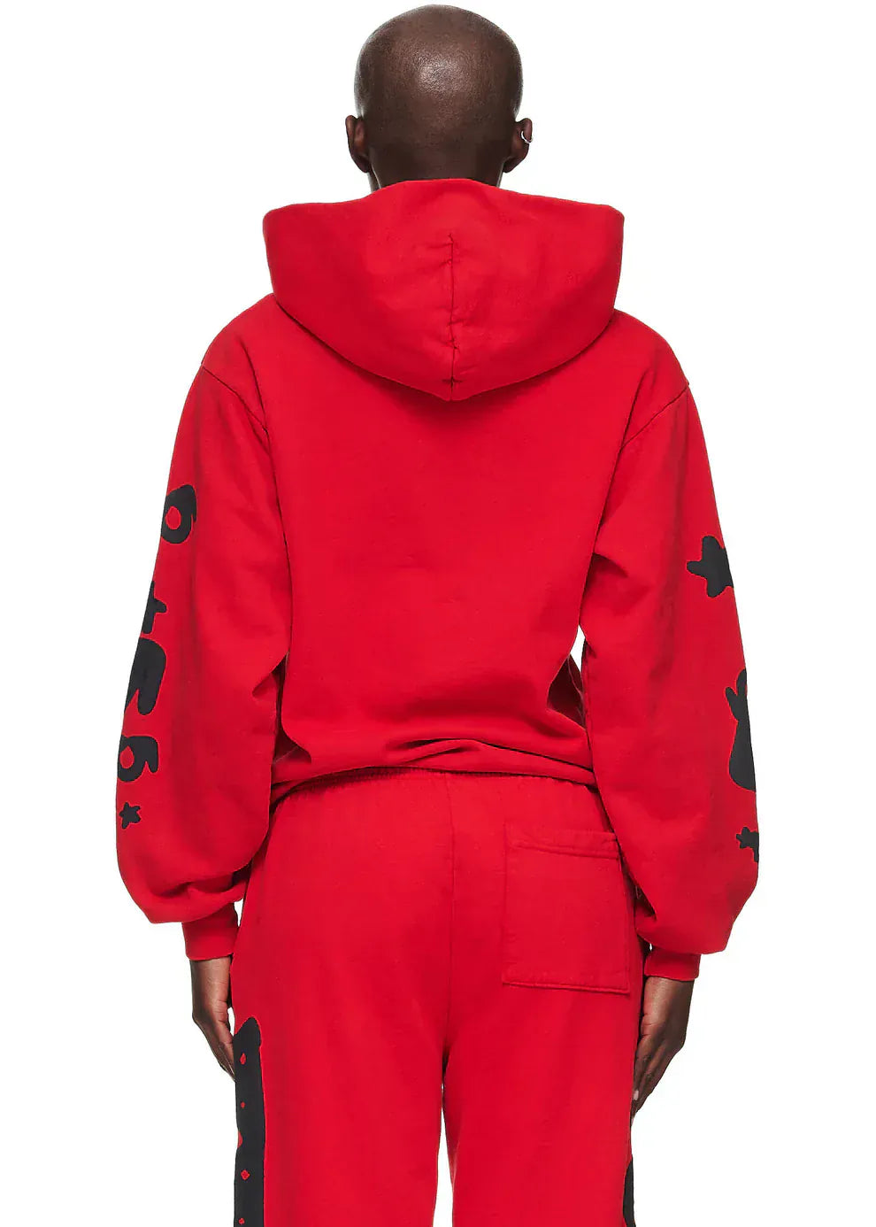 A person stands with their back to the camera, wearing a Sp5der “Starfire” Hoodie – Red & Black 440GSM Heavyweight Oversized Pullover, and matching red pants featuring black graphics on the sleeves and legs.