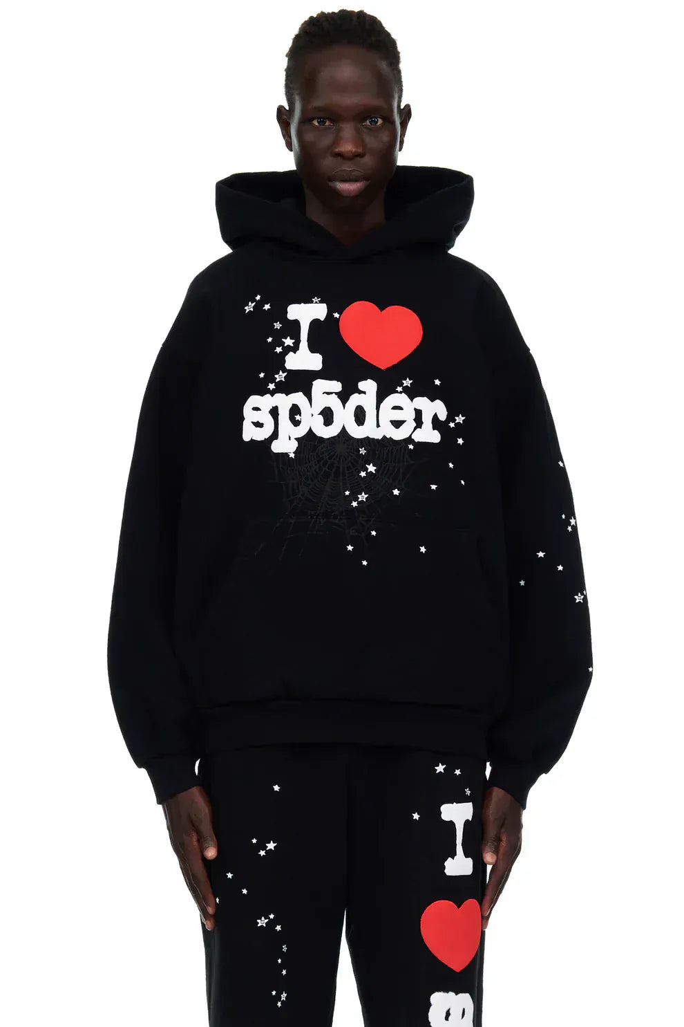 Wearing the Sp5der “I Love Sp5der” Hoodie – Black Web 440GSM Heavyweight Pullover and black pants with white and red "I ♥ sp5der" star graphics, ideal for bold streetwear or Y2K-inspired outfits.