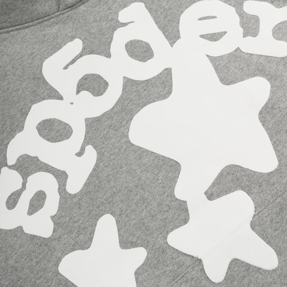 Close-up of the Sp5der Stars Hoodie in grey, a 440GSM heavyweight streetwear pullover made from cotton fleece, featuring white abstract shapes and partially visible "spder" text.