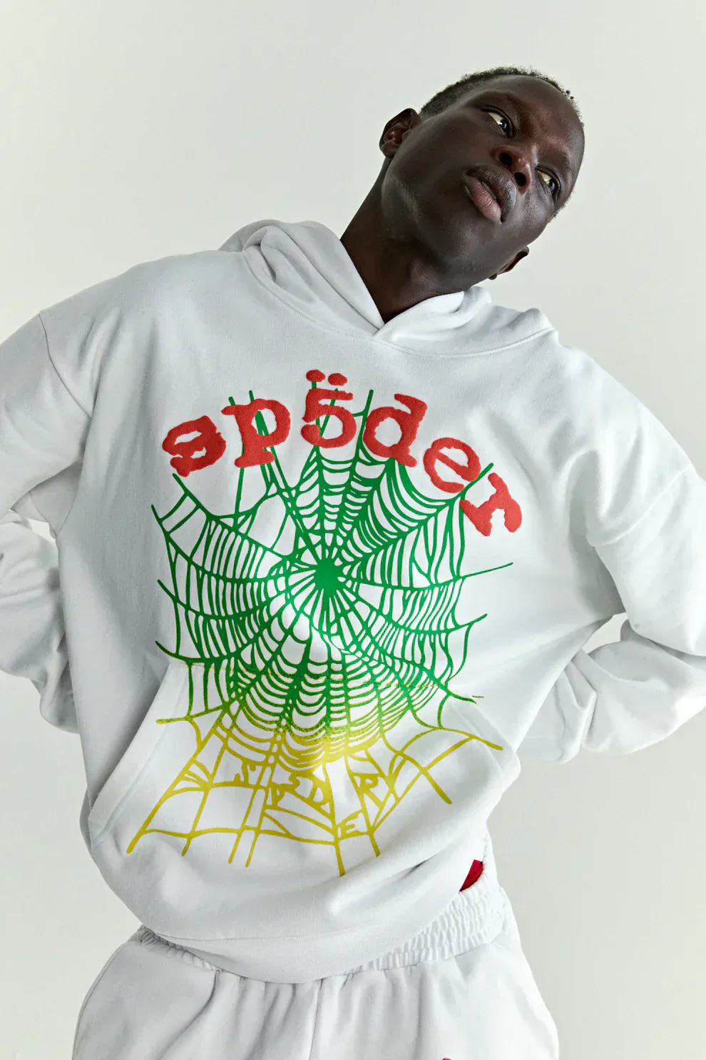 Person wearing a Sp5der “Toxic Web” Hoodie – White & Neon Lime 440GSM Heavyweight Oversized Streetwear Pullover with colorful web graphics and red "spider" text, perfect for Y2K streetwear, standing against a light background.