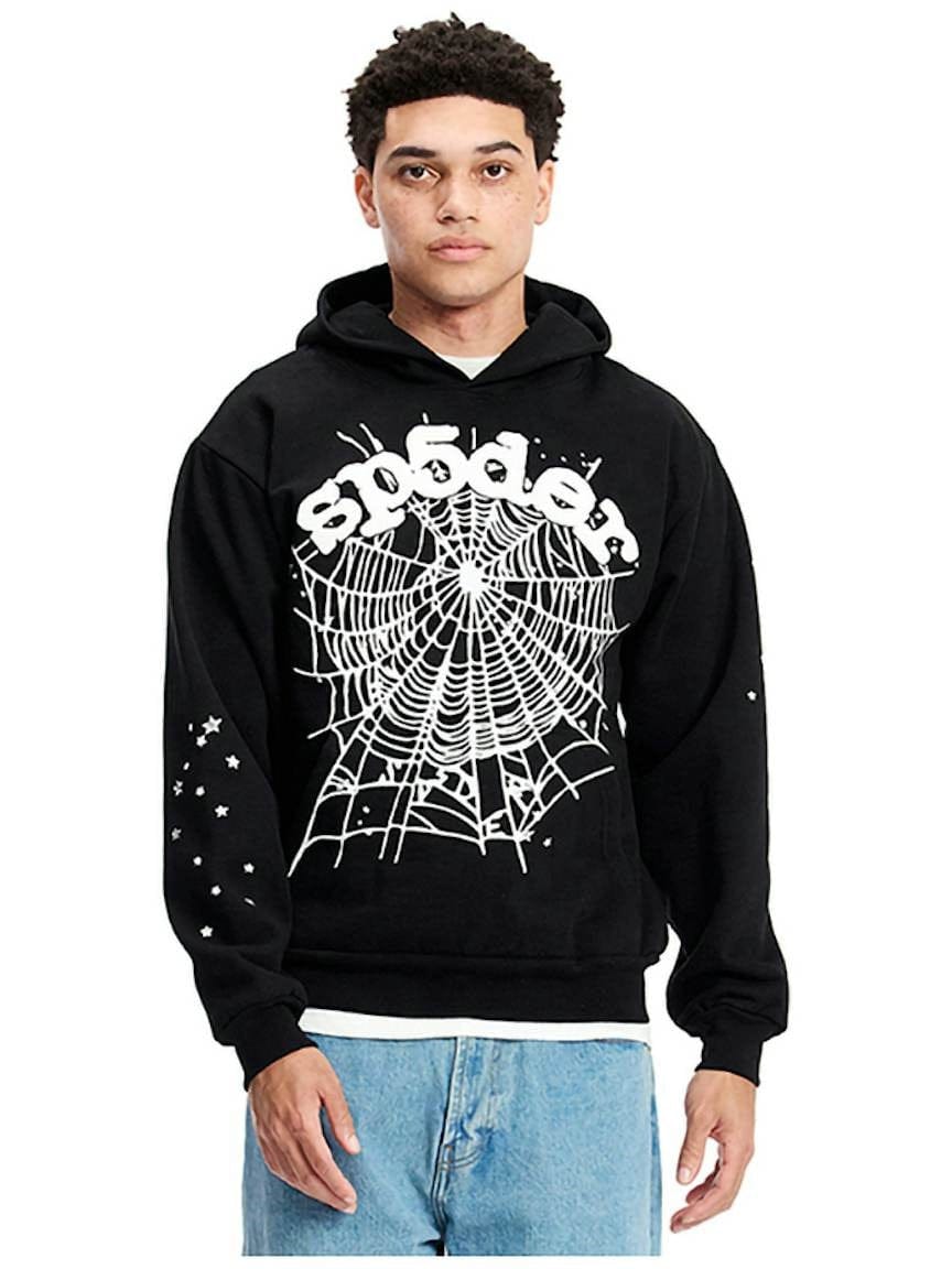 A person wearing the Sp5der "Webcore Noir" Hoodie – a black & white 440GSM heavyweight oversized streetwear pullover with a large spider web, "sp5der" graphic on the front, and white star designs on the sleeve.