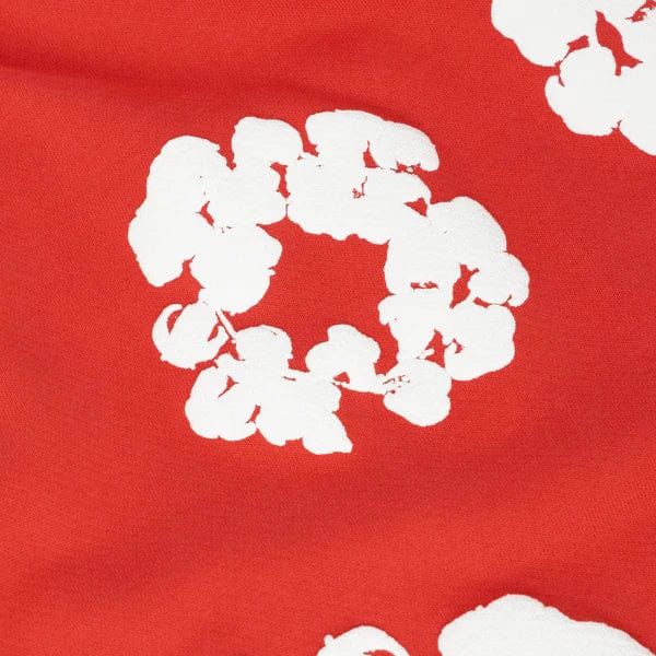 Red “Cotton Wreath” Denim Tears Sweatpants feature white abstract floral prints on a red background, bringing bold streetwear style to these unique pants.