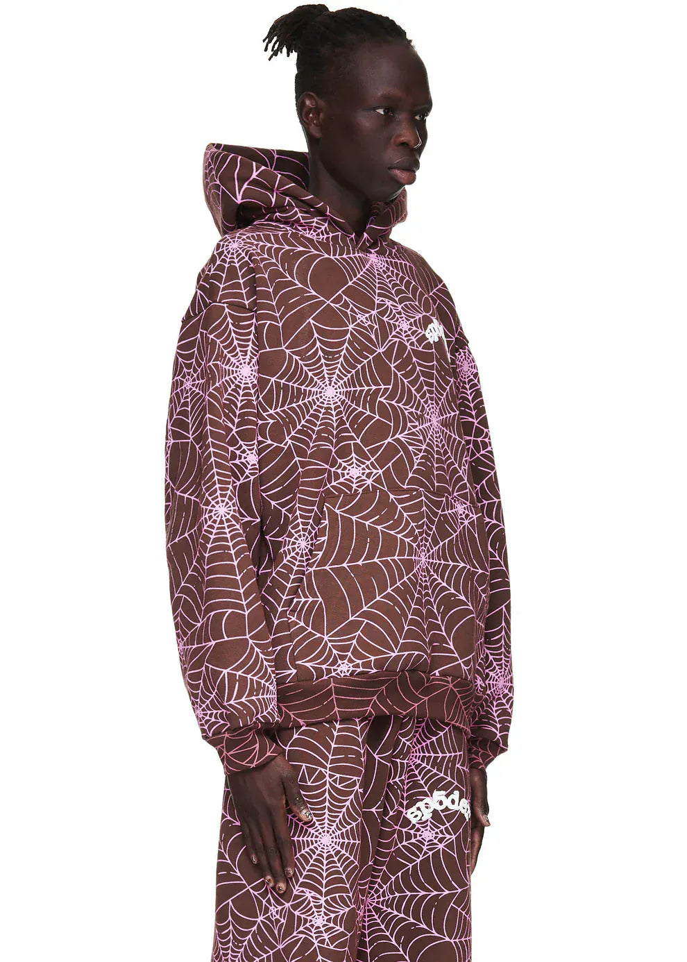 A person wearing the Brown All-Over Spider Web Graphic Hoodie – Comfort Fit Pullover Hoodie and matching sweatpants with a pink spider web print, standing against a plain background.