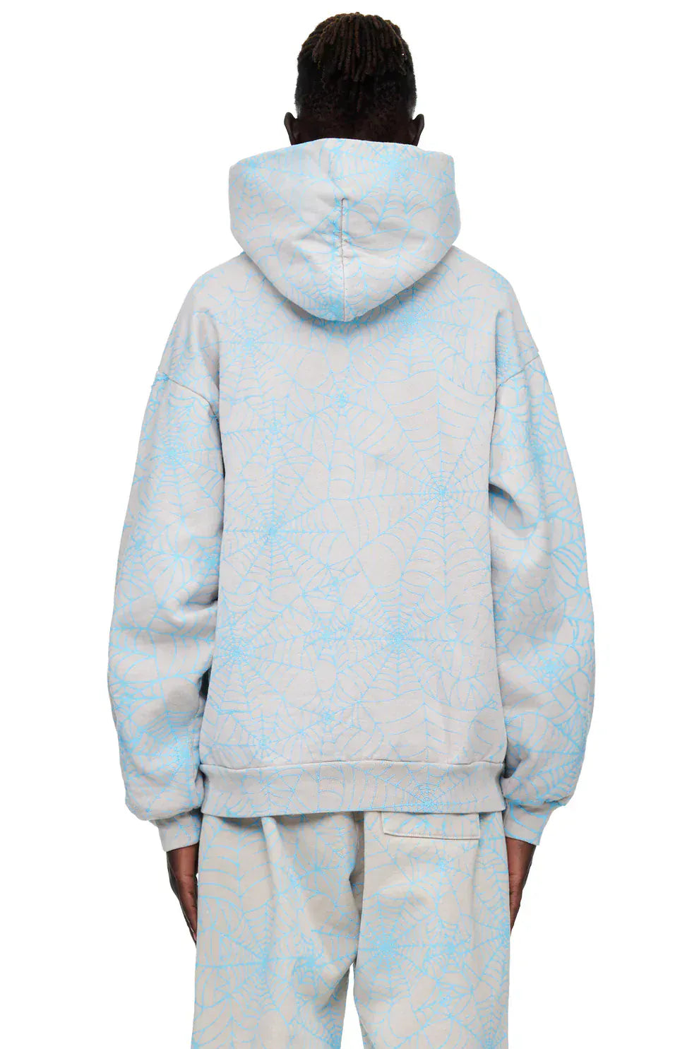 Person standing with their back to the camera, wearing the Light Grey All-Over Spider Web Graphic Hoodie – a comfort fit pullover with a bold blue spider web print design.