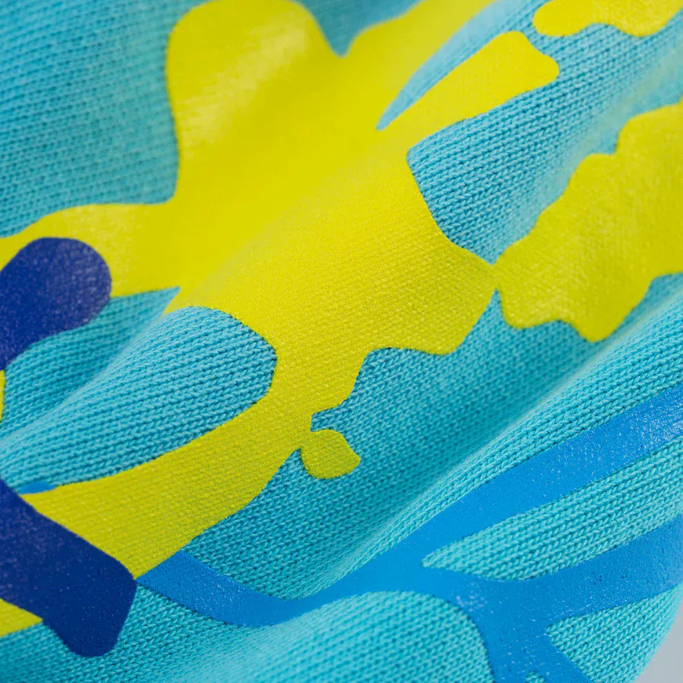 Close-up of turquoise graphic hoodie fabric from the Comfort Fit Pullover Hoodie, featuring star detail and spider web back print, with visible texture and raised ink design.