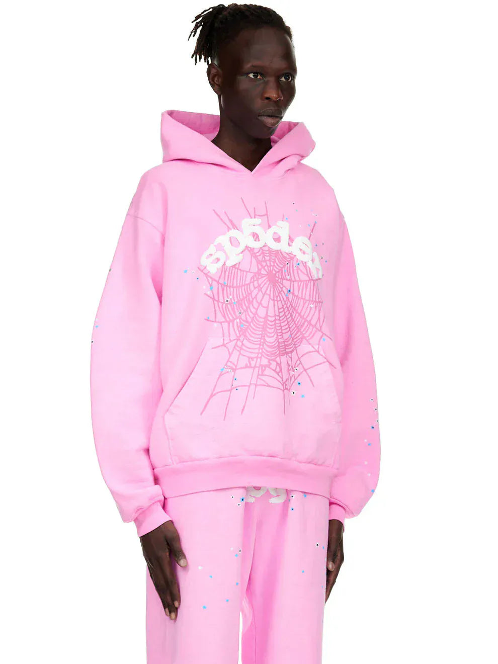 Model wears the Pink Graphic Hoodie with Spider Web Print – Comfort Fit Pullover Hoodie, featuring bold spider web and sp5der text graphics for a standout streetwear look against a white background.