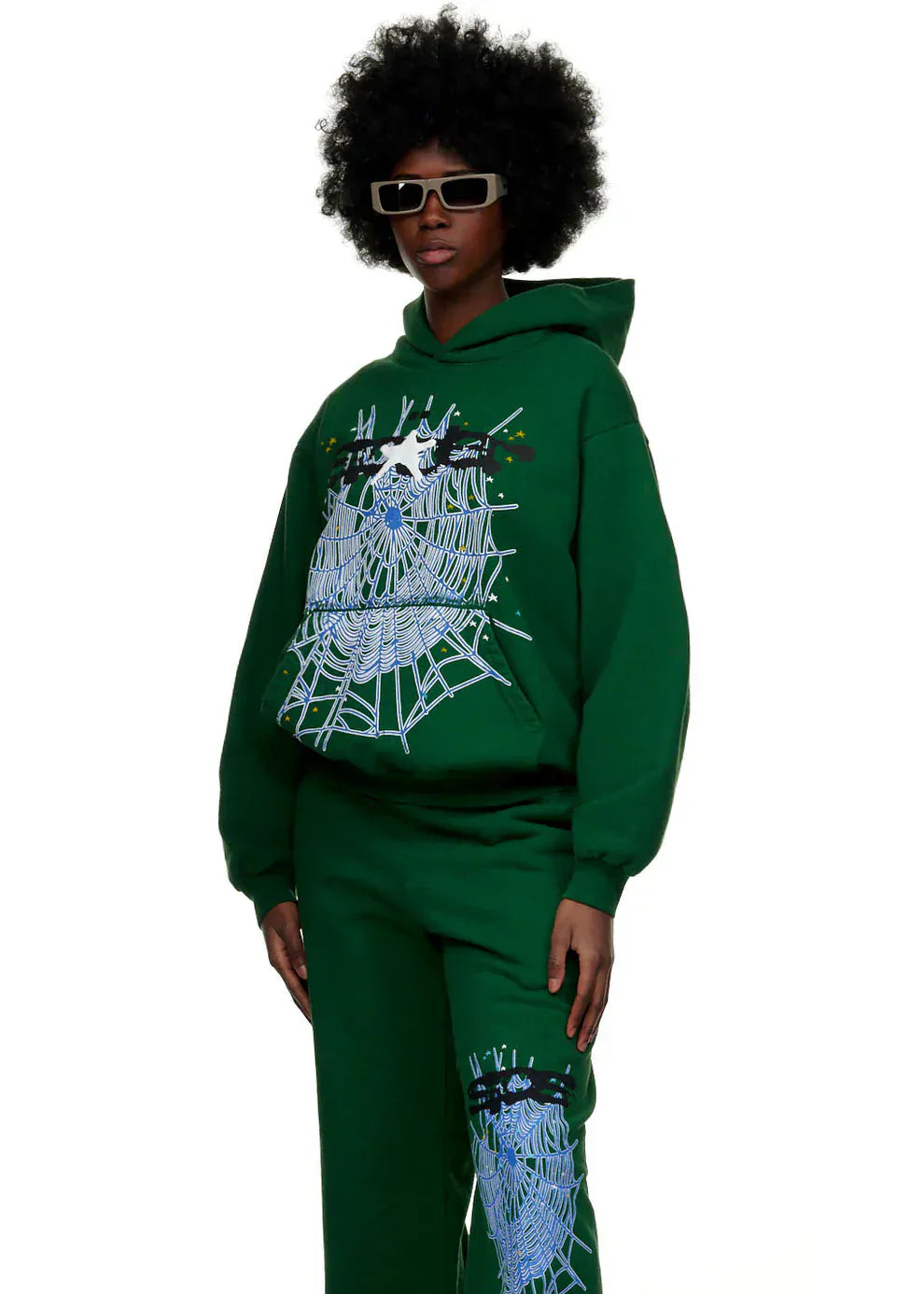 Model wearing the Dark Green Graphic Hoodie with Spider Web Print—an everyday comfort fit pullover—paired with matching pants and rectangular sunglasses, stands against a white background for a bold streetwear look.