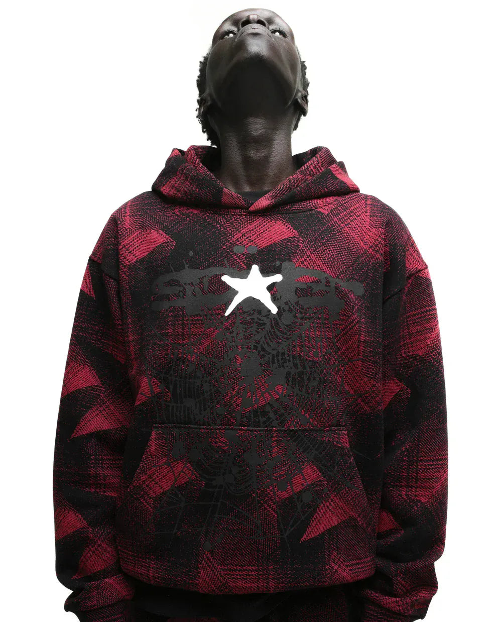 Model wearing the Red and Black Graphic Hoodie with Star Detail and Spider Web Print—a comfort fit pullover featuring bold streetwear style—against a white background, looking upward.