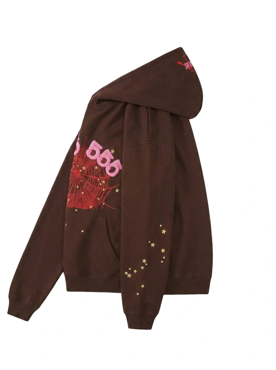 The 555 Brown Spider Hoodie (Sp5der 555 Web Brown/Pink) is a heavyweight oversized pullover with a pink “555” graphic, red web design, and yellow star accents on the sleeve and body, shown from the side.