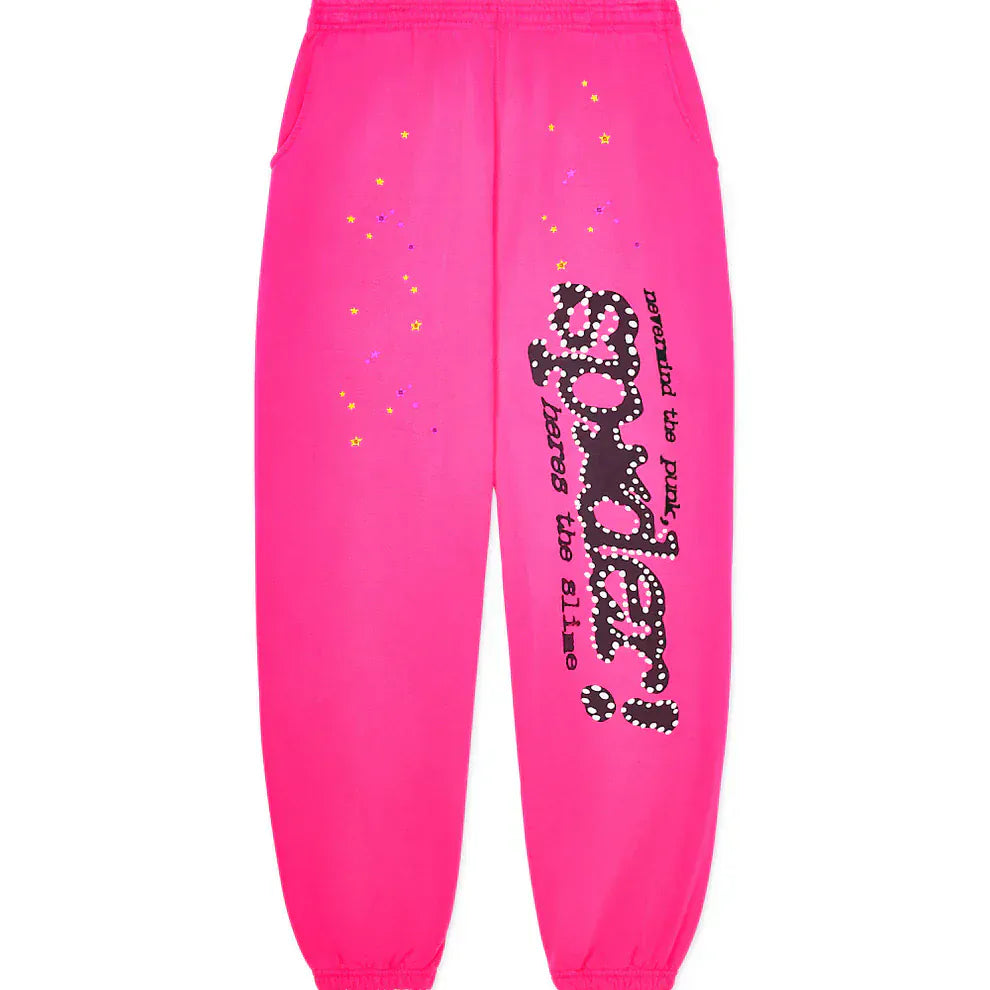 Unisex Sp5der Sweatpants in bright pink cotton, featuring a wide leg, graphic logo print with black, white, and purple "spider!" text and star graphics on one leg; finished with elastic waistband and cuffs.