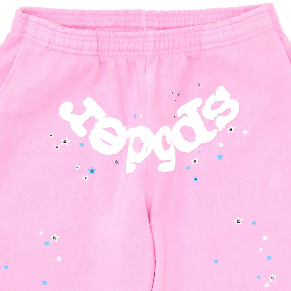 Sp5der Sweatpants – Unisex light pink cotton joggers featuring a front logo and blue, white, and black star prints, with an elastic waistband for comfort.