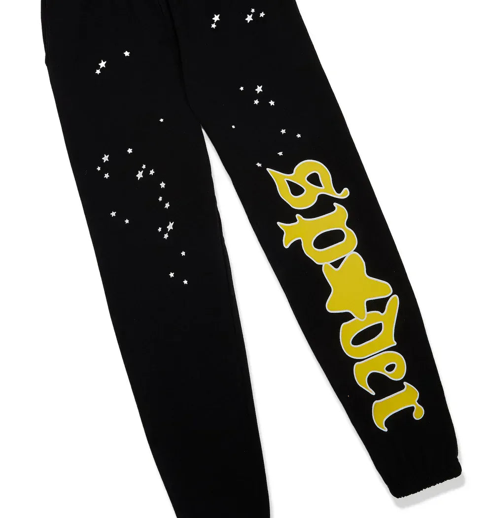 100% Cotton Sp5der Sweatpants for Men—black streetwear jogger pants with scattered white stars and a bold yellow logo graphic, featuring a relaxed fit perfect for modern men's fashion.