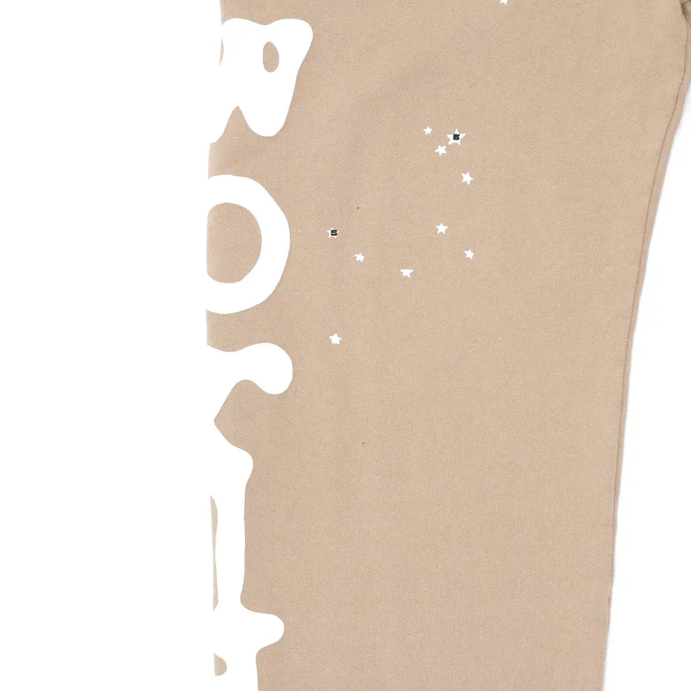 Close-up of 100% cotton Sp5der sweatpants for men in beige, featuring a side logo graphic on relaxed fit streetwear jogger pants.