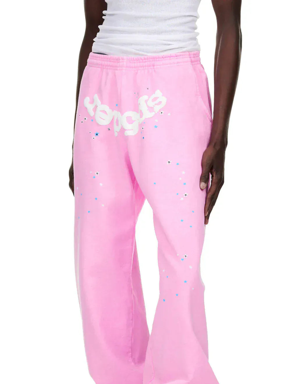 Person wearing Sp5der Sweatpants – unisex light pink cotton sweatpants with front logo and star print, styled with a white ribbed tank top for a standout streetwear look.