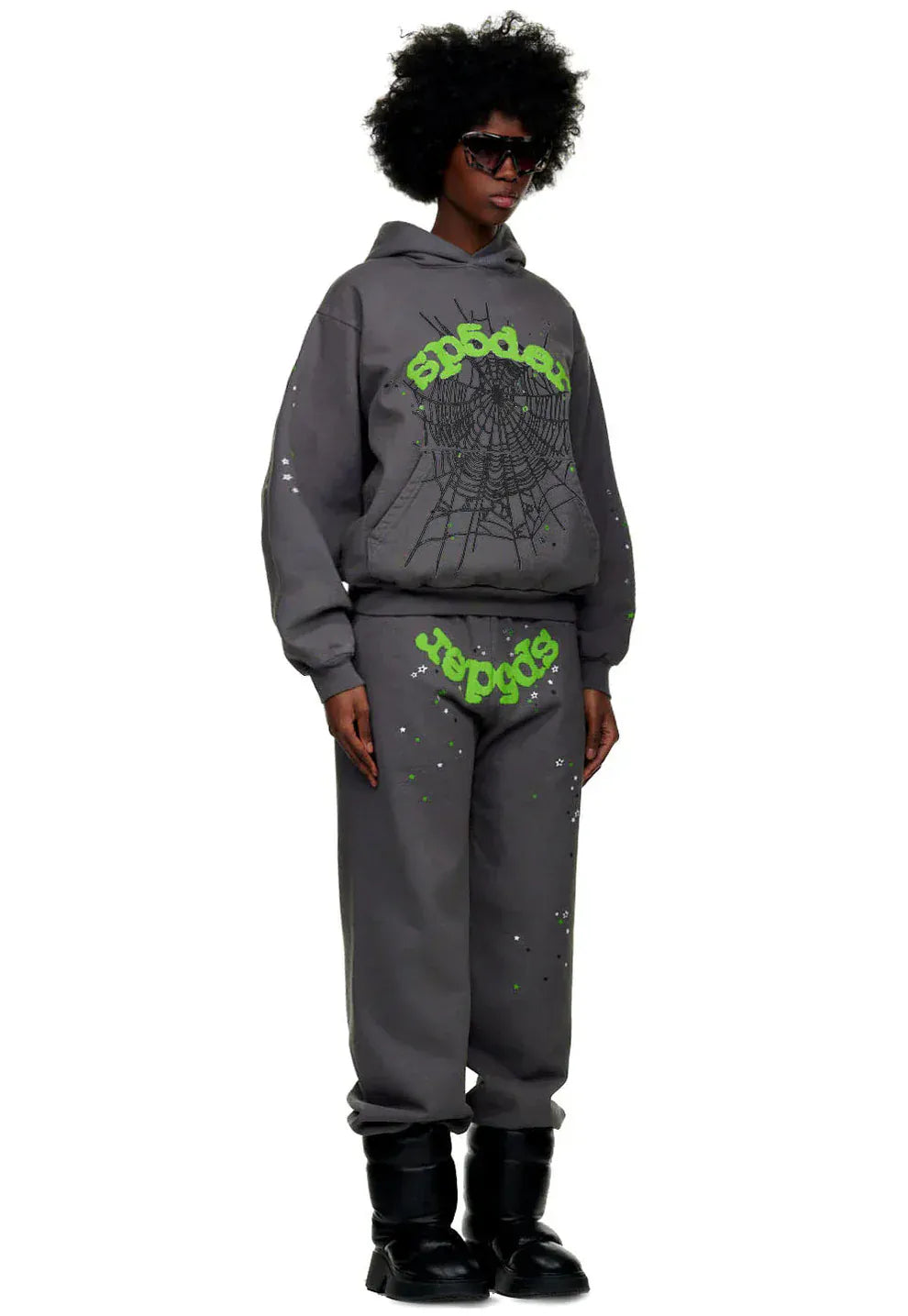 A person in a dark gray hoodie and 100% Cotton Sp5der Sweatpants for Men—dark grey jogger pants with green logo graphic, relaxed fit—plus black sunglasses and boots, stands against a plain background for a bold streetwear look.