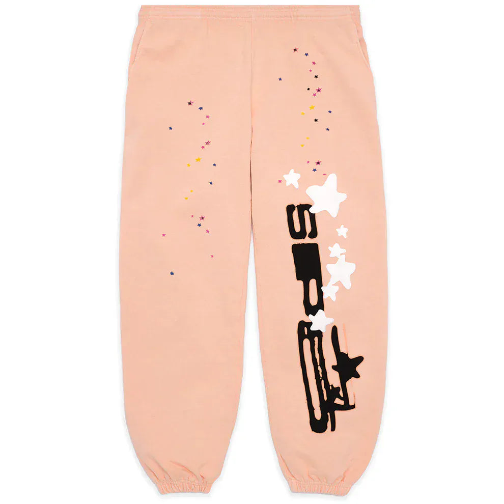 Unisex 100% cotton Sp5der peach jogger pants with a relaxed fit, vertical logo, black and white abstract star graphics, and scattered colorful dots on the front.