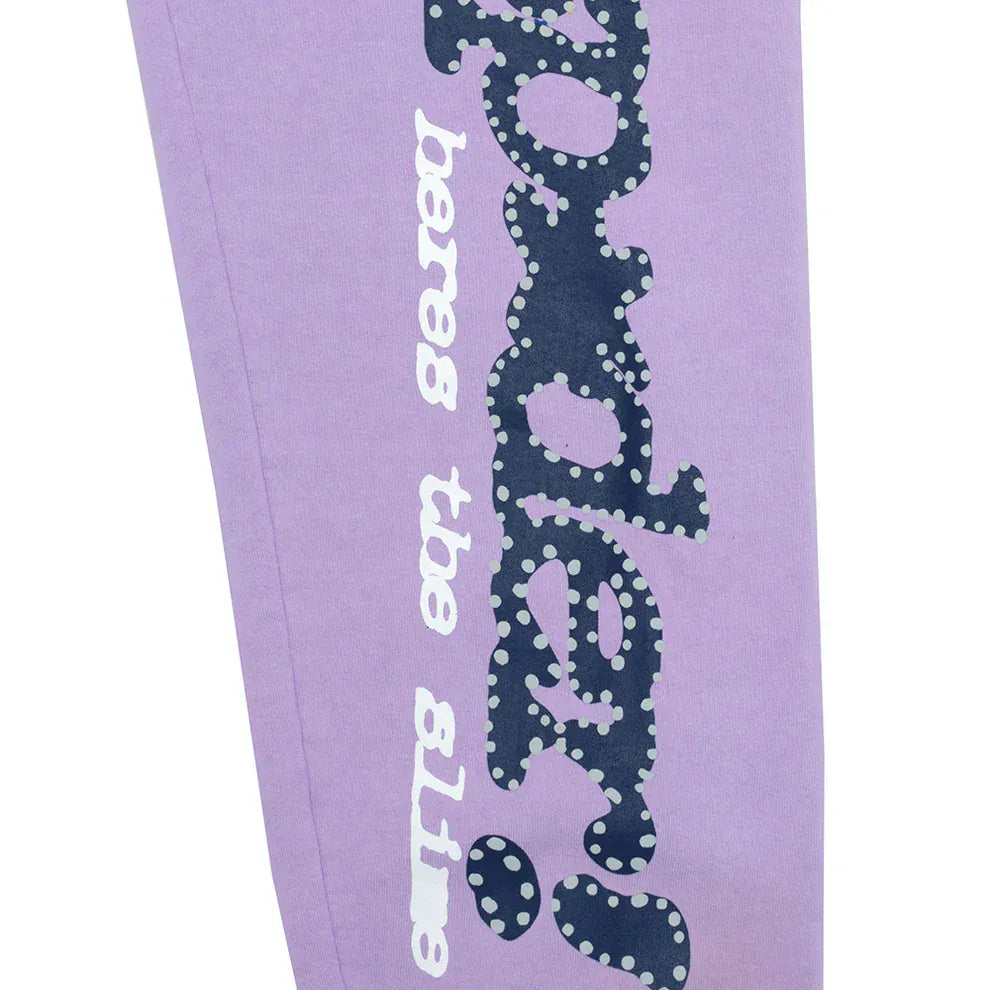 Close-up of lavender Sp5der sweatpants featuring a vertical logo and star details, made from 100% cotton in a relaxed, unisex fit—ideal for everyday streetwear or pairing with your favorite top.
