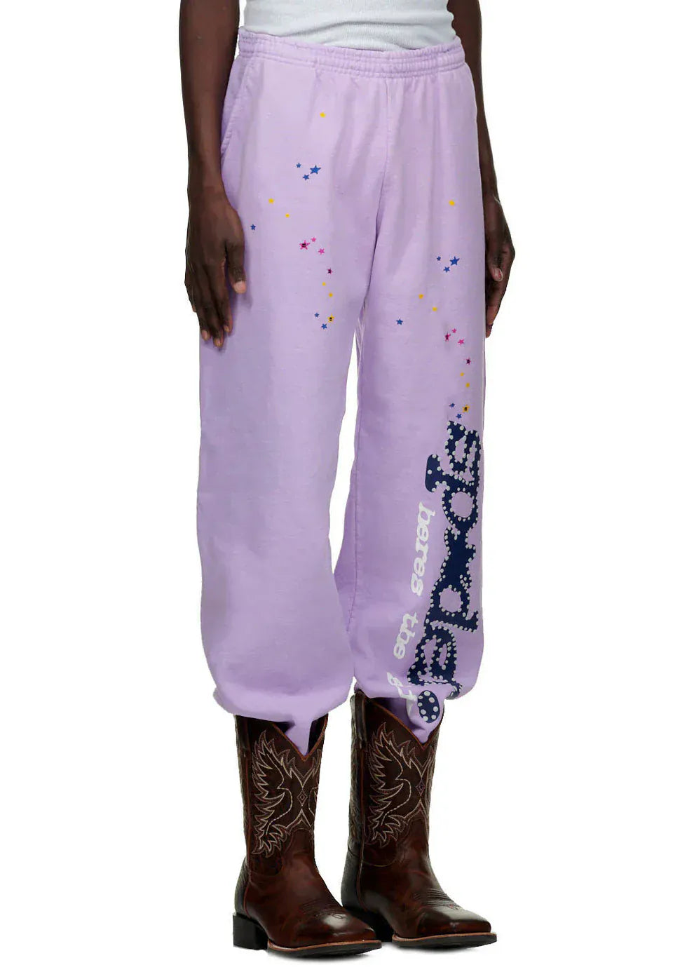 Person wearing 100% Cotton Sp5der Sweatpants—Unisex Lavender Jogger Pants with vertical logo and star details, relaxed fit—paired with brown cowboy boots for a bold streetwear look.