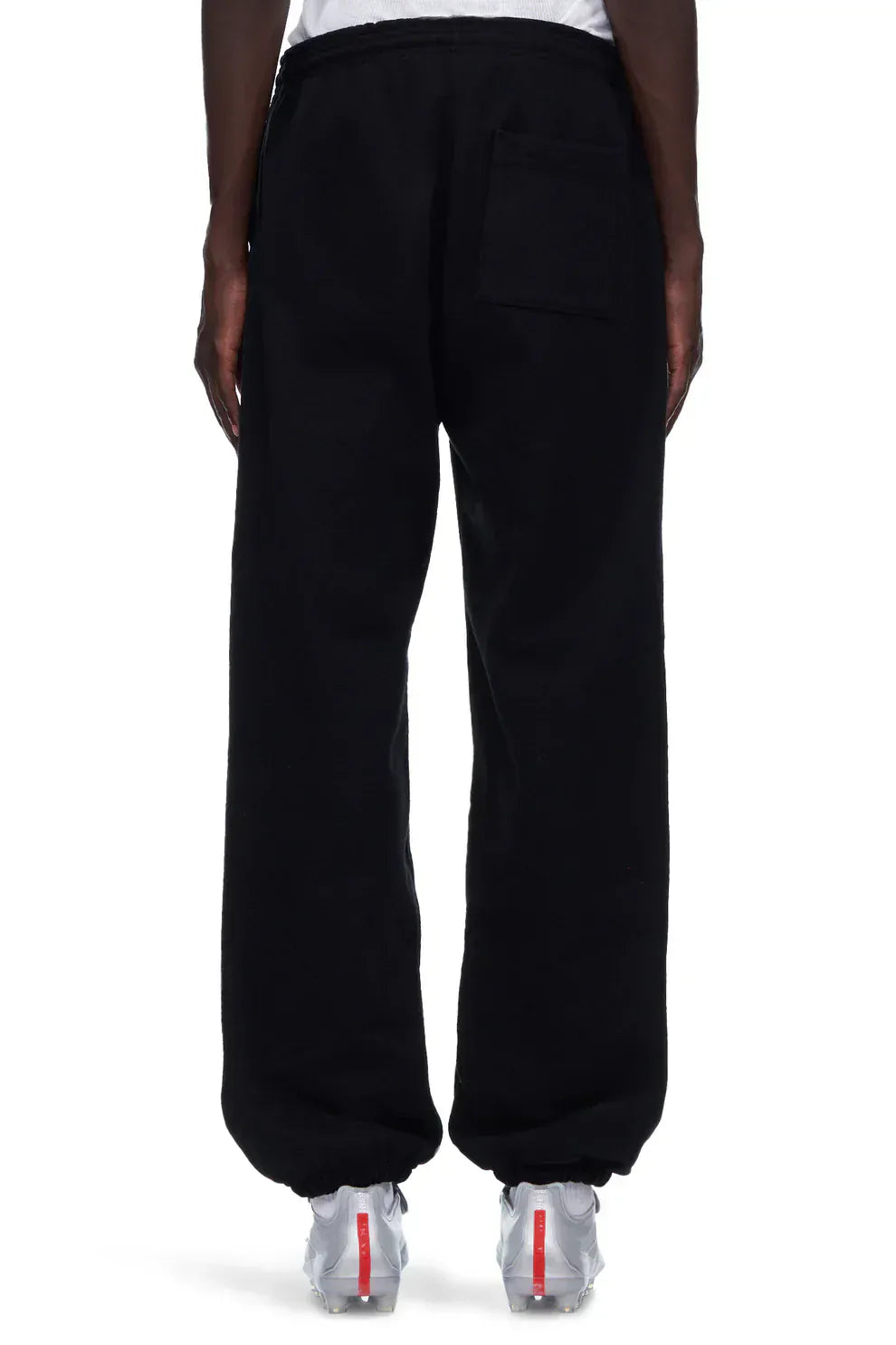 Model wears 100% Cotton Sp5der Sweatpants – Unisex Black Jogger Pants with “I Love Sp5der” graphic, relaxed fit and back pocket, paired with white sneakers, shown from the rear against a plain background.