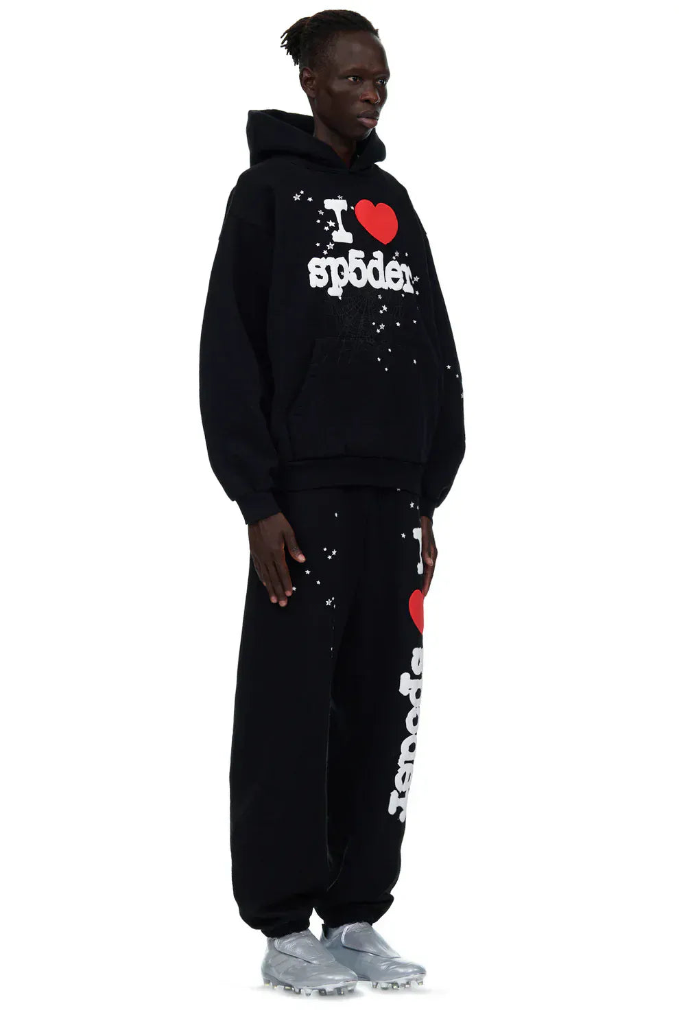 A person stands facing forward in a black hoodie and unisex black 100% cotton Sp5der sweatpants featuring a white paint splatter and “I Love Sp5der” graphic, designed for a relaxed fit.