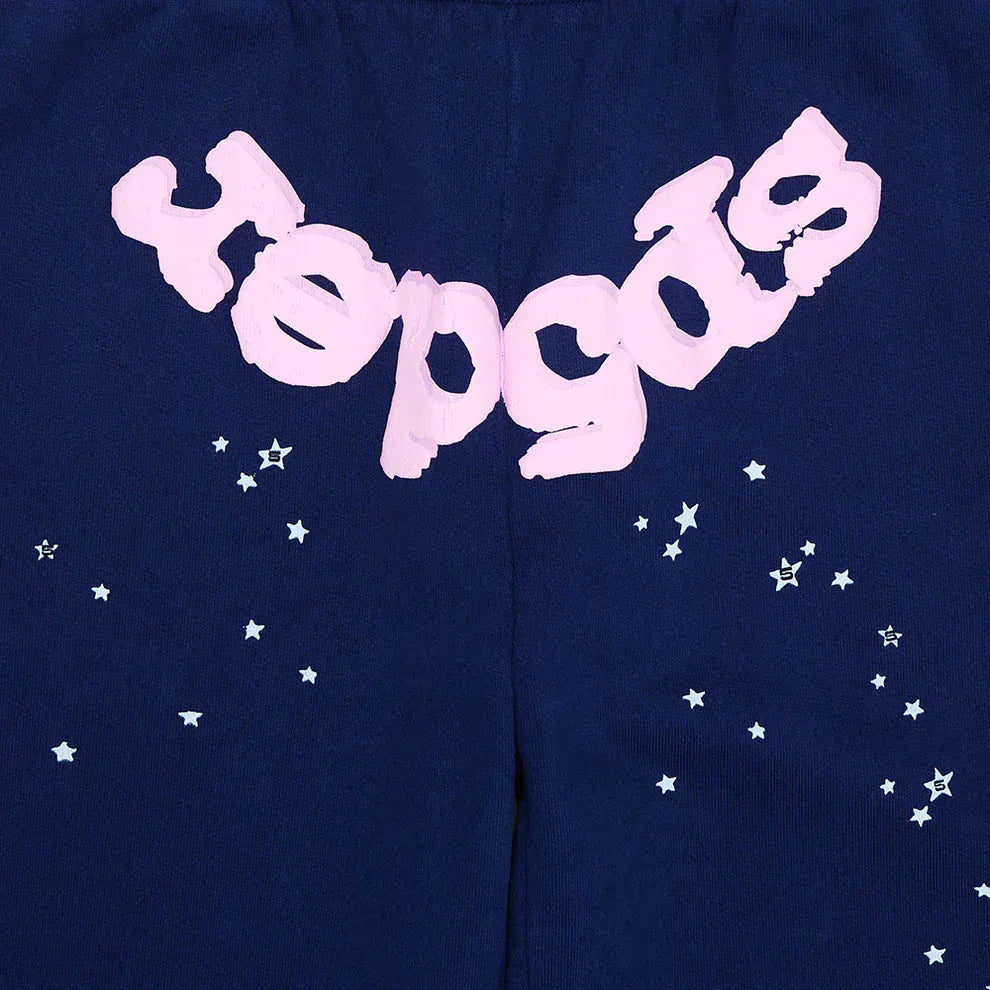 These 100% cotton Sp5der sweatpants are unisex navy blue jogger pants featuring a light pink logo reading "Hepçəz" and scattered white star graphics for an eye-catching, relaxed-fit streetwear look.