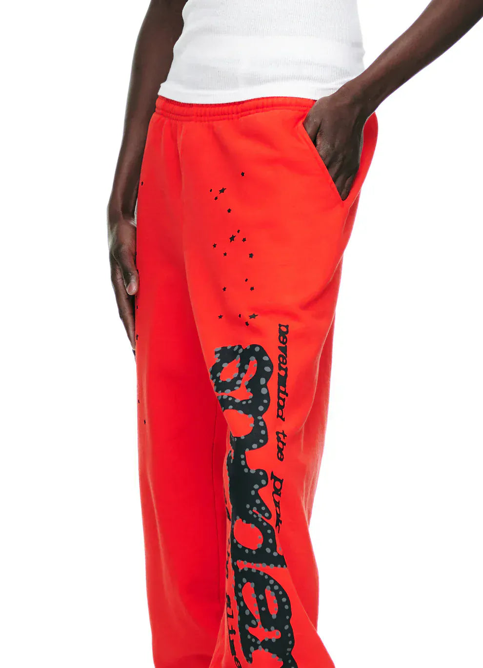 A person wearing 100% Cotton Sp5der Sweatpants—Unisex Red Jogger Pants with Black Logo and Star Graphics, Relaxed Fit—perfect bold streetwear for those who love standout unisex cotton joggers.
