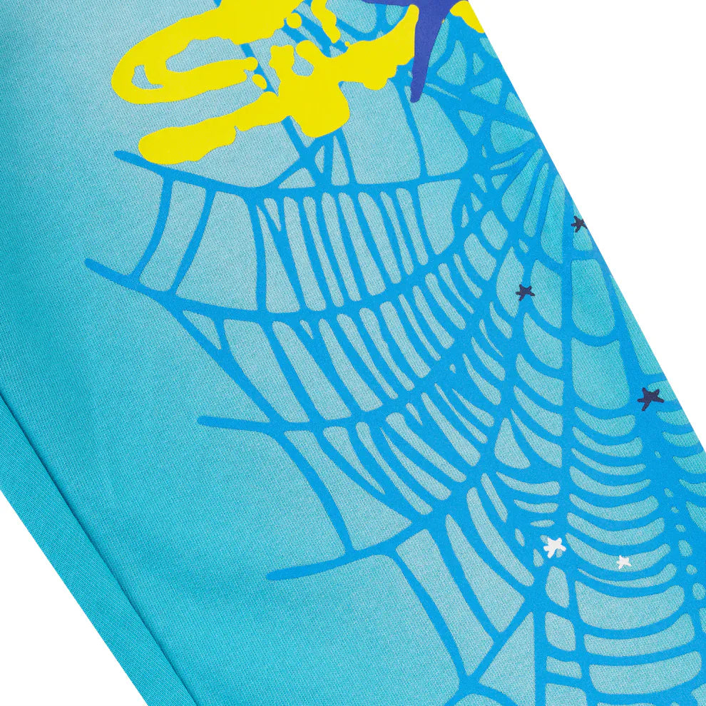 Close-up of 100% Cotton Sp5der Sweatpants—Unisex Blue Jogger Pants with a spider web graphic, star details, and yellow accents. These relaxed fit sweatpants offer comfort and standout streetwear style.
