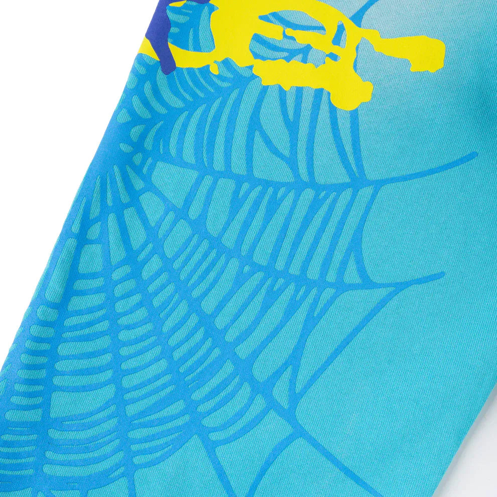 Close-up of 100% Cotton Sp5der Sweatpants—Unisex Blue Jogger Pants with a light blue spider web graphic, star details, and a partially visible yellow graphic on the top left; features relaxed fit streetwear style.