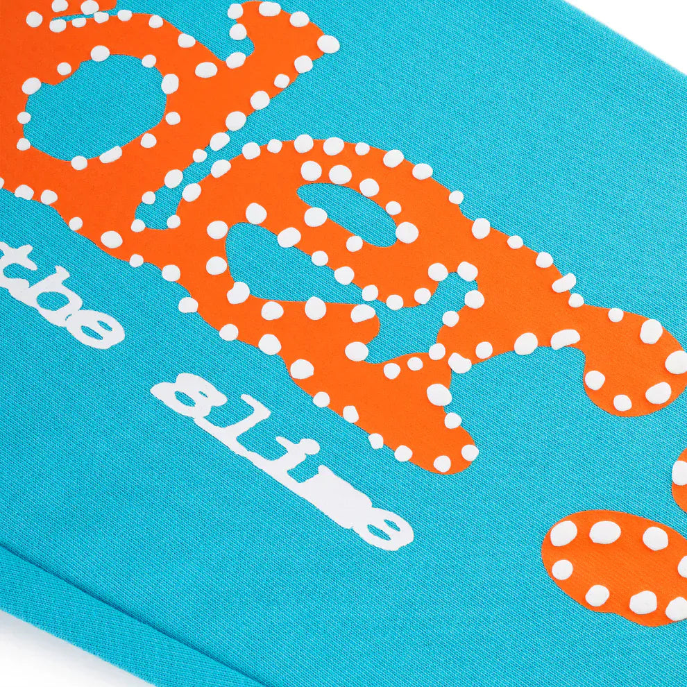 Close-up of unisex Sp5der teal jogger pants, made from 100% cotton, featuring an orange logo print and relaxed fit for a casual streetwear look.