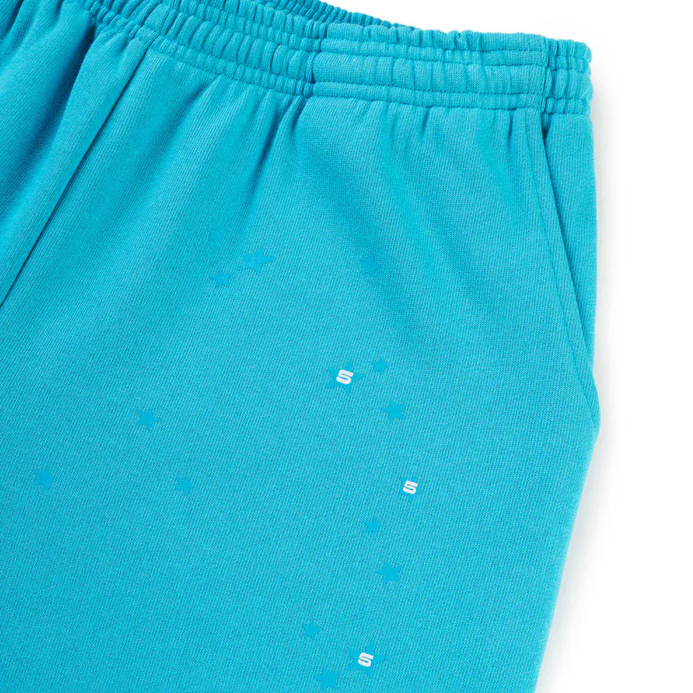Close-up of 100% Cotton Sp5der Sweatpants—unisex teal jogger pants featuring an elastic waistband, side pocket, relaxed fit, and orange logo print on the fabric.