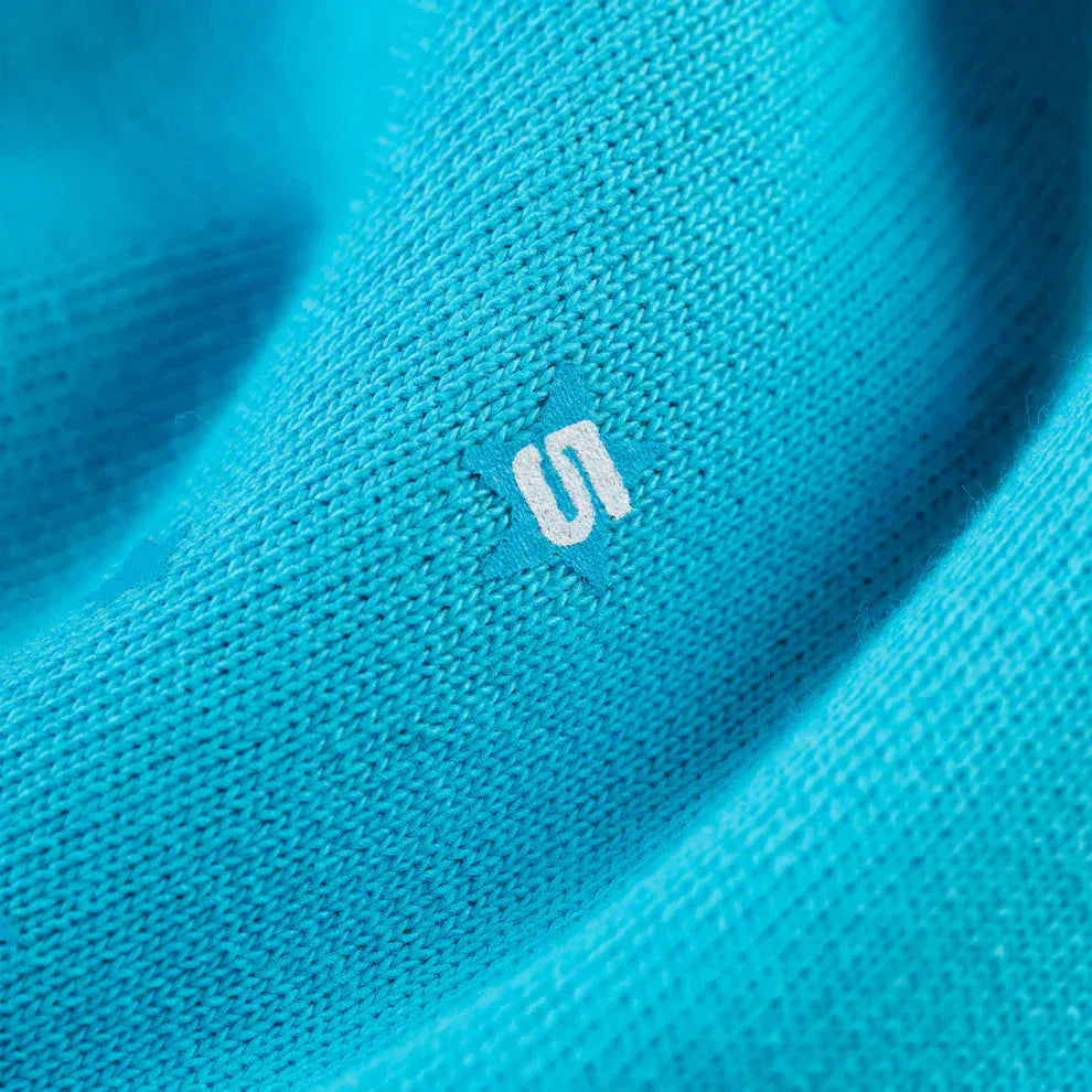 Close-up of 100% Cotton Sp5der Sweatpants—unisex teal jogger pants with a relaxed fit and an orange logo print, perfect for fans of streetwear style.