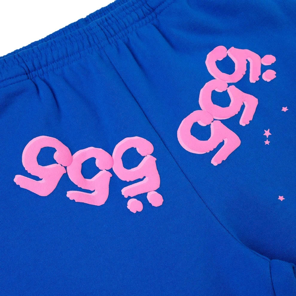 Unisex 100% cotton Sp5der sweatpants in blue with a relaxed fit, featuring pink logos and star accents inspired by streetwear jogger styles.