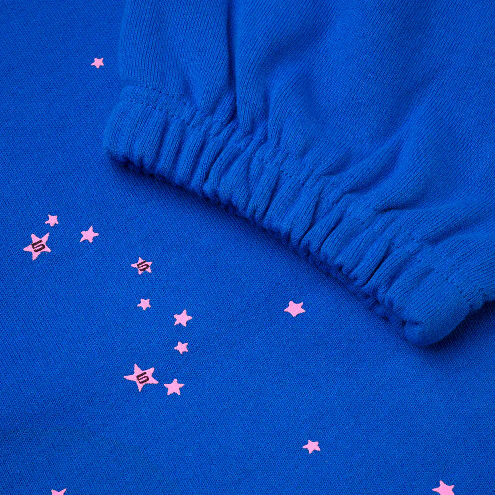 Close-up of 100% Cotton Sp5der Sweatpants – Unisex Blue Jogger Pants featuring pink logo and star accents, relaxed fit, and elastic cuffs—ideal for streetwear enthusiasts.