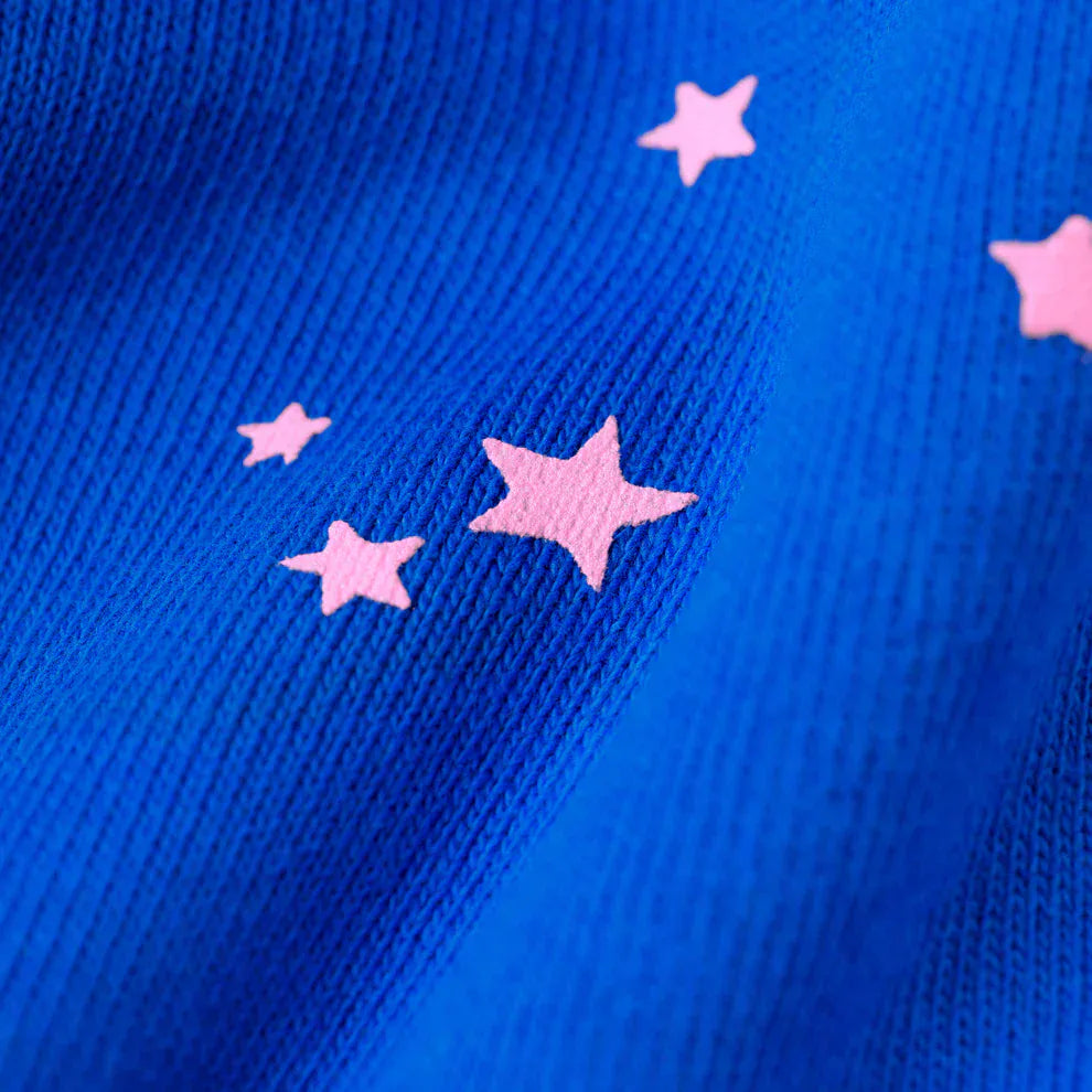 Close-up of 100% Cotton Sp5der Sweatpants—unisex blue jogger pants with a relaxed fit, showcasing ribbed fabric and pink logo with star accents.