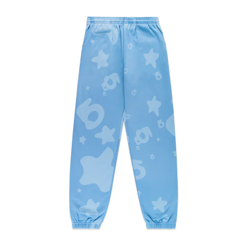 The Sp5der Light Blue All-Over Print Sweatpants are unisex 100% cotton streetwear joggers with an elastic waistband and cuffs, detailed with stars, numbers, and abstract shapes in a slightly darker blue.