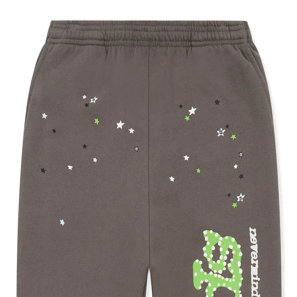 Sp5der Sweatpants – Unisex dark grey cotton sweatpants with an elastic waistband, featuring a green side logo and scattered white, black, and green star prints for standout streetwear flair.