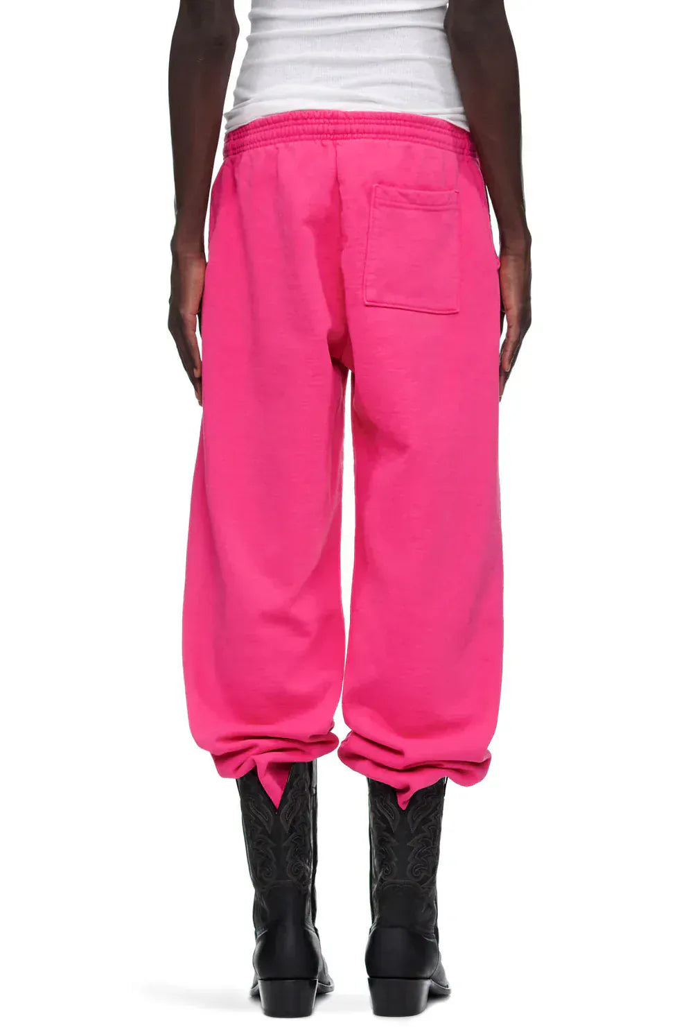 Person shown from the back in Sp5der Sweatpants – Unisex Pink Cotton Wide Leg Sweatpants with graphic logo print, elastic waistband, single back pocket, paired with black boots.
