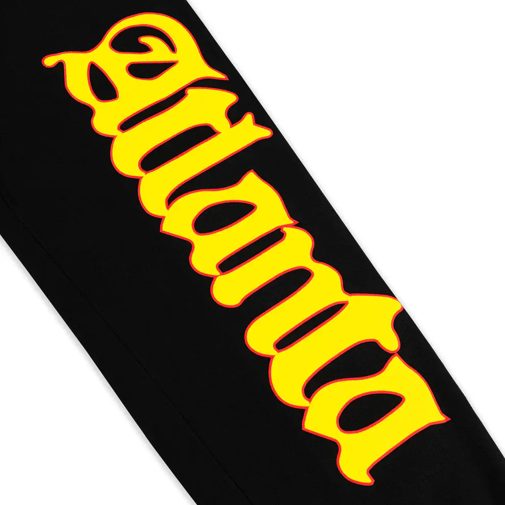The Sp5der Sweatpants – Unisex Black Cotton Sweatpants feature a bold flame logo and star print on the sides, making them a standout piece for any streetwear joggers collection.