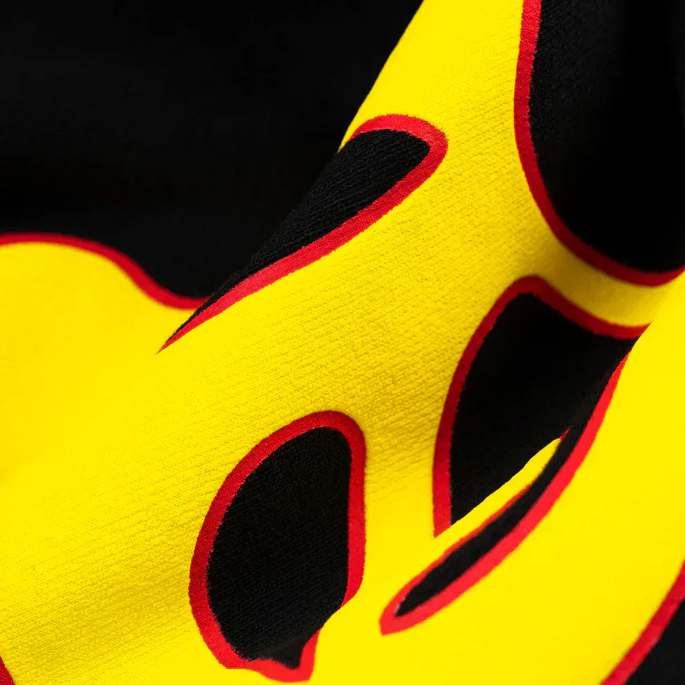 Close-up of black cotton Sp5der Sweatpants, unisex with a bold flame side logo and star print, showcasing vibrant graphic details and streetwear-inspired style.