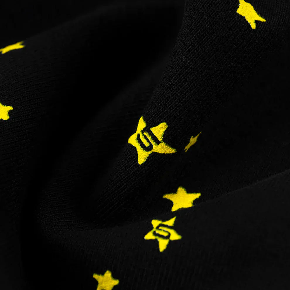Close-up of Sp5der Sweatpants—unisex black cotton joggers featuring a flame side logo and a star print, including yellow stars with "S" inside—perfect for adding standout style to your streetwear collection.