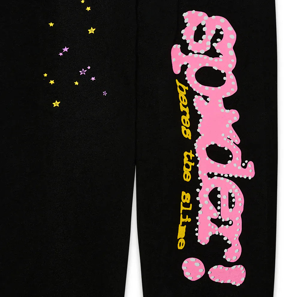 The Sp5der Sweatpants—unisex black cotton with a pink graphic logo and yellow star print—pair perfectly with streetwear, featuring bold yellow "beware the slime" text beneath the standout "spyder!" branding.